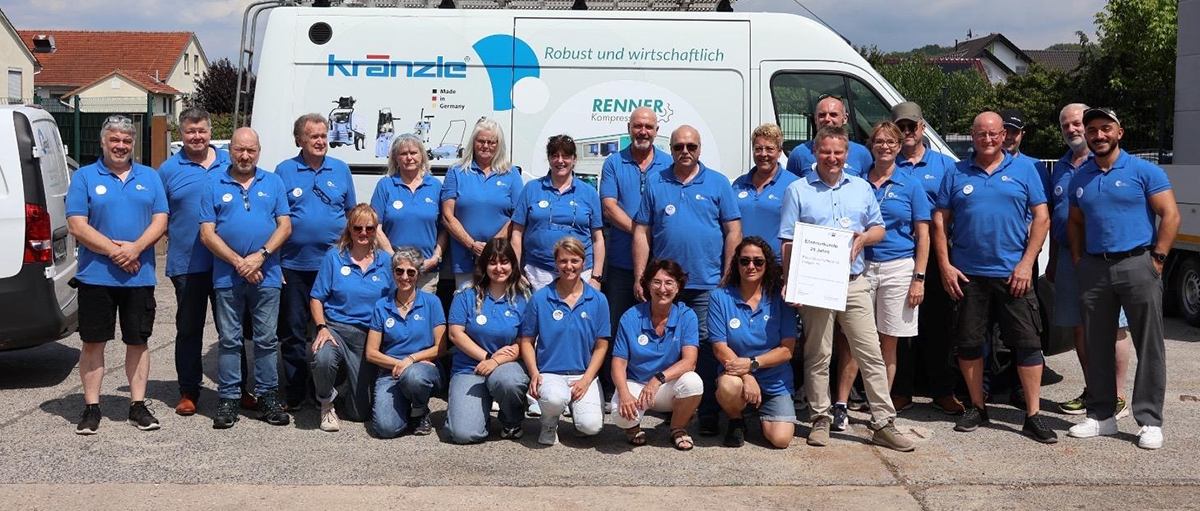 Die Belegschaft von Fassl Drucklufttechnik in blauen Firmenhemden vor einem Servicefahrzeug auf dem Betriebshof in Freigericht-Horbach