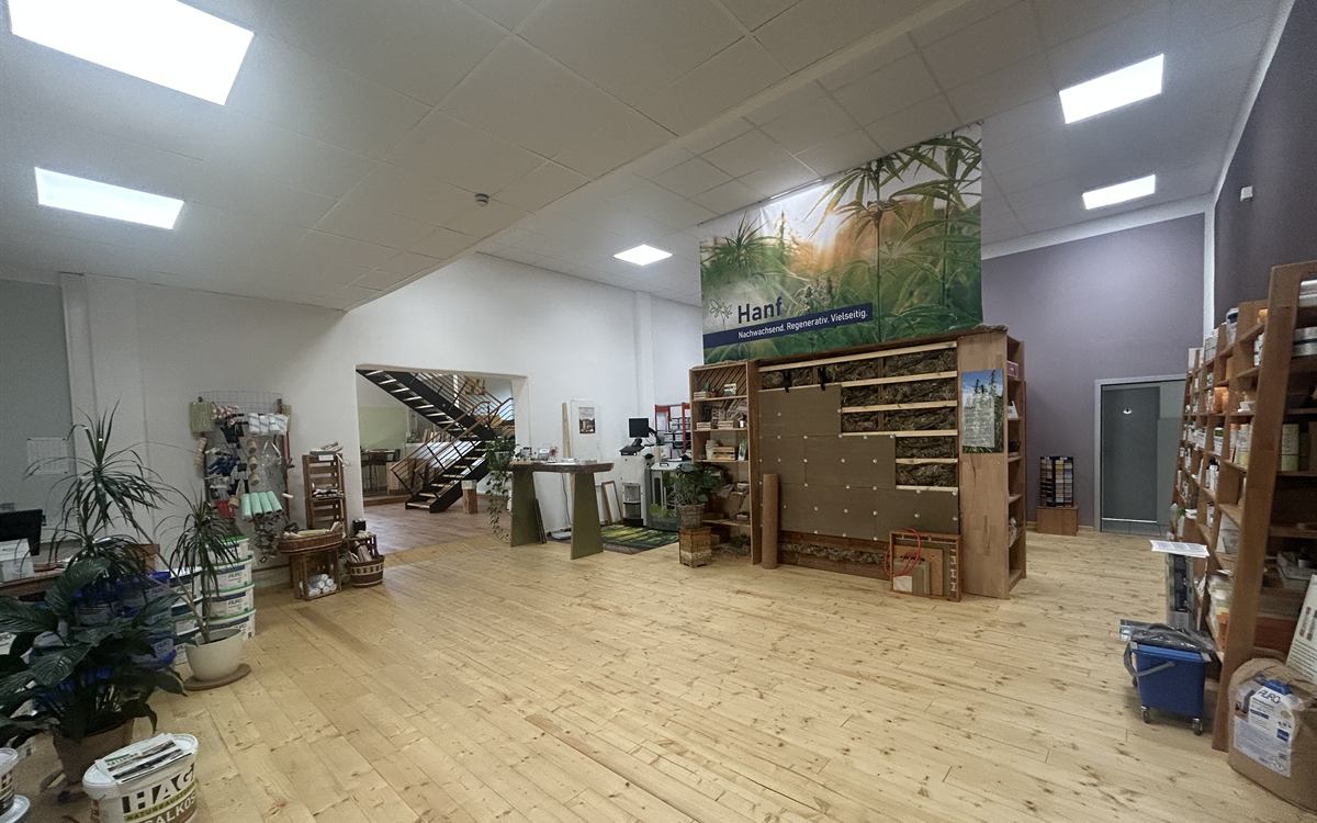 Blick in die Ausstellung in Wetzlar-Nauborn: Musterwand mit Hanfd&auml;mmung unter dem Hanf-Banner, ringsum Regale mit Naturfarben